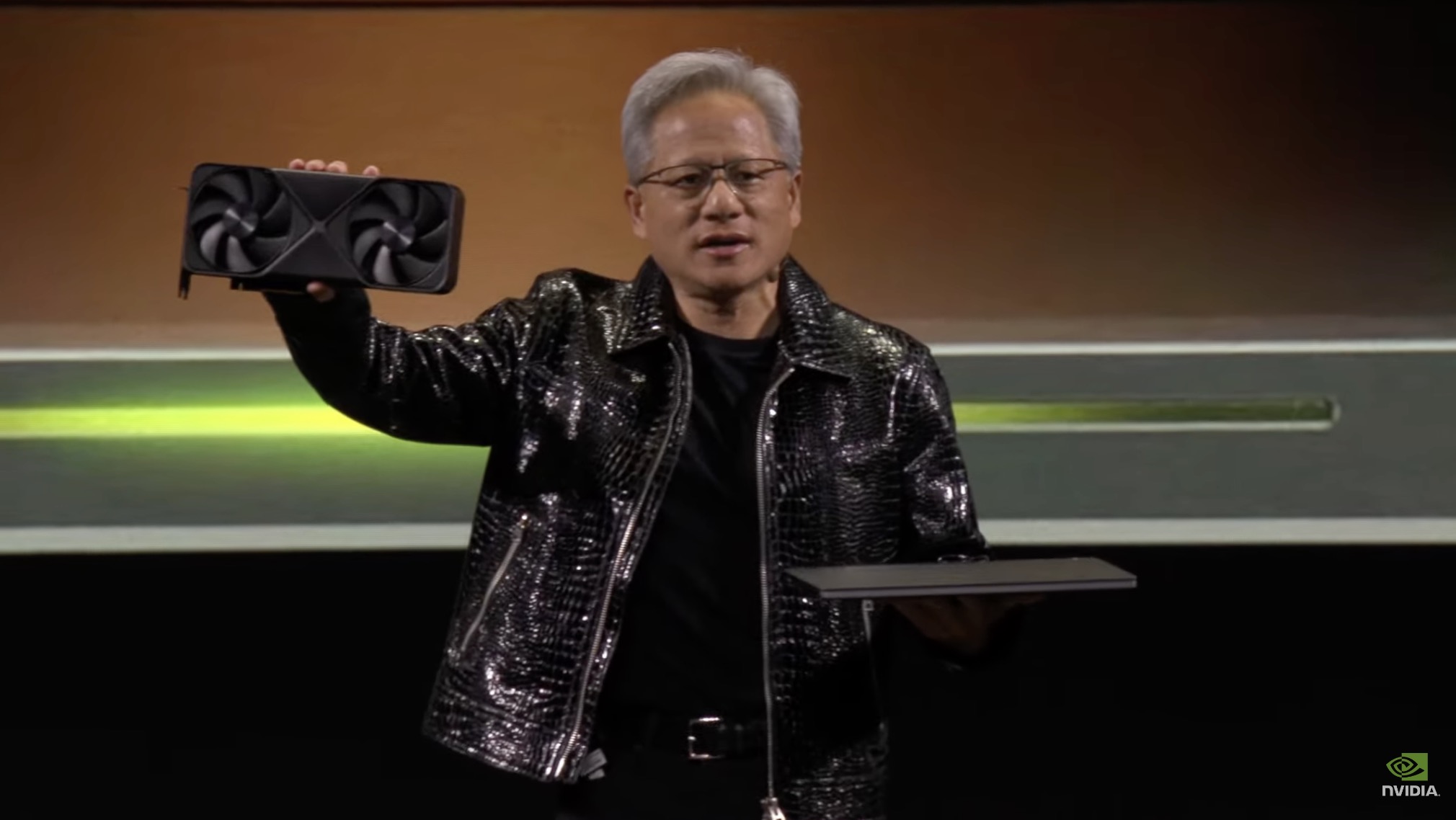 Nvidia CEO Jensen Huang holding an RTX 50 GPU and a laptop.