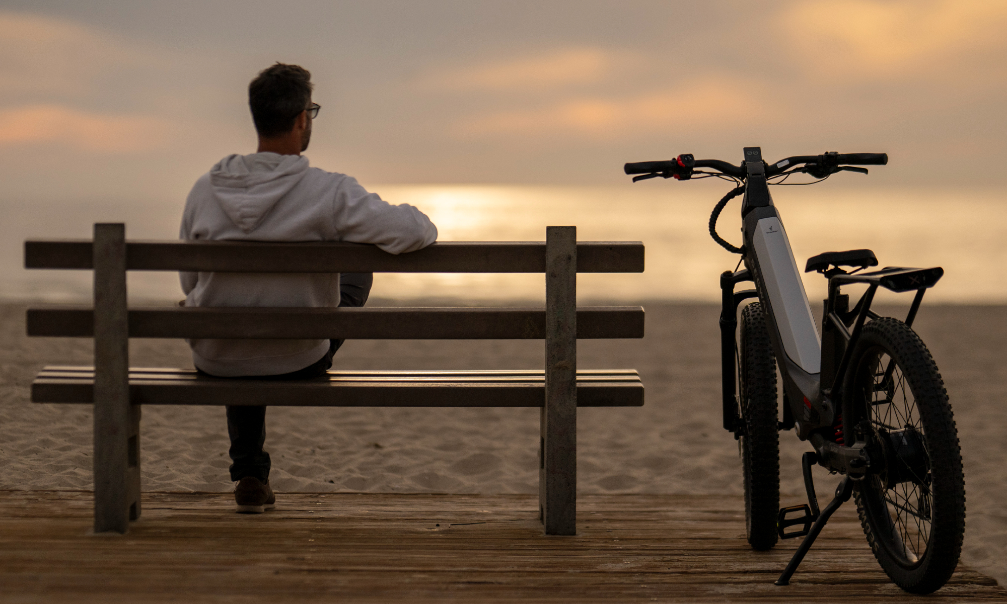 Segway Xafari e-Bike garé près d'un banc à la plage avec une personne assise sur le banc.