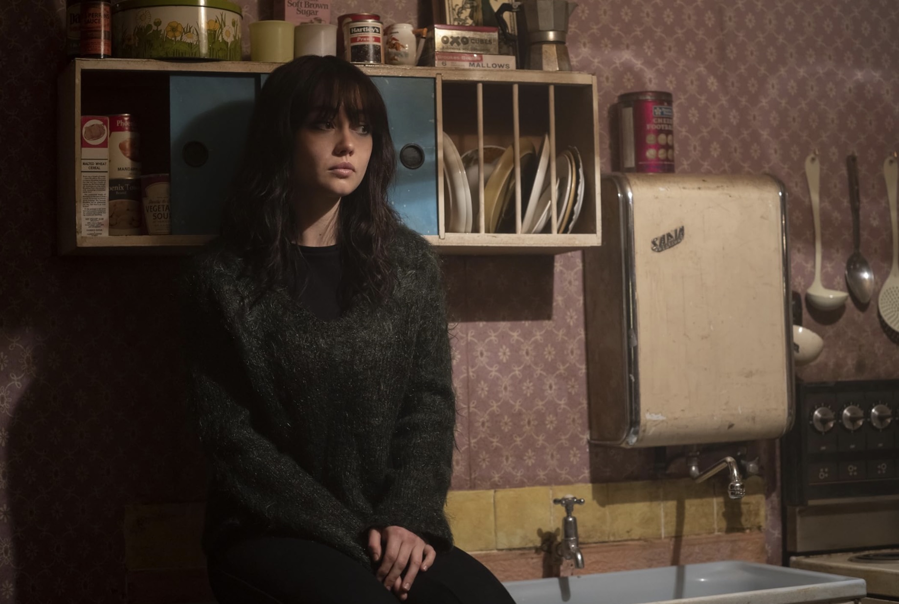 A woman sits on a counter in Pistol.