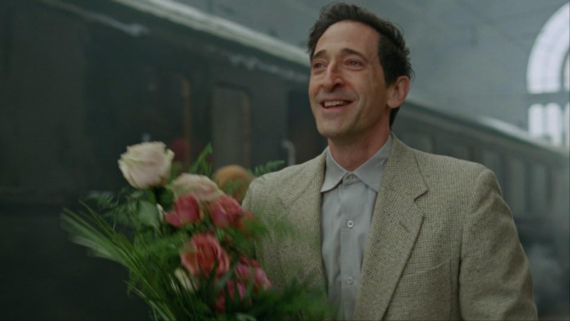 Un homme tient un bouquet de fleurs dans The Brutalist.