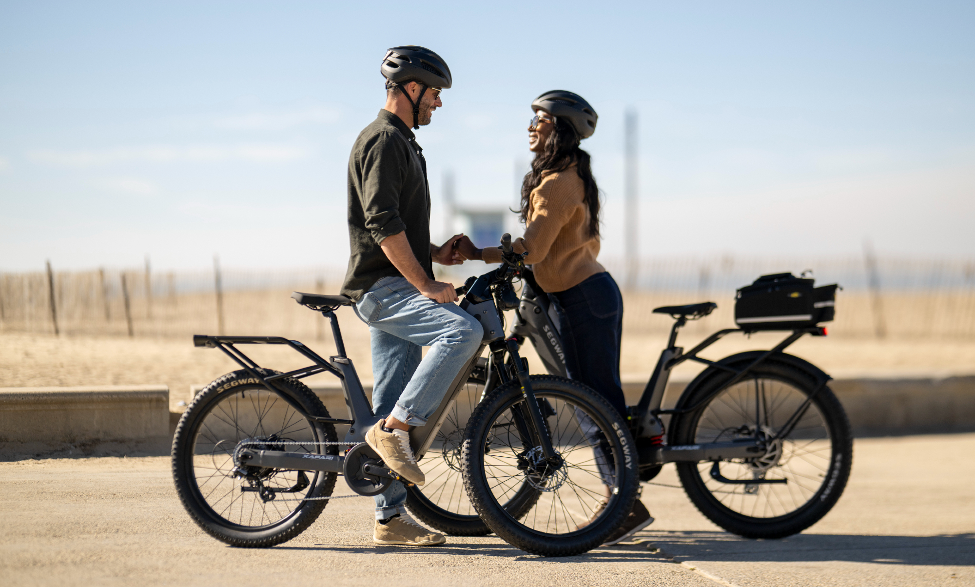 Deux personnes avec des vélos électriques Segway Xafari se font face avec une plage floue en arrière-plan.