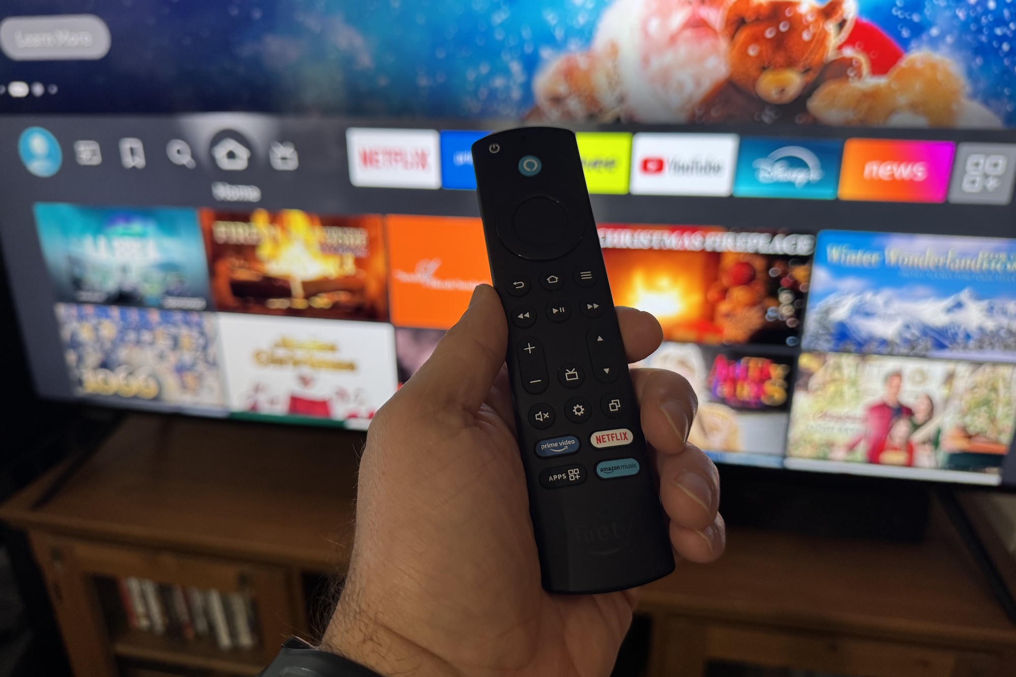 Une main tenant la télécommande Amazon Fire TV devant le téléviseur Amazon Fire TV Omni Mini-LED.