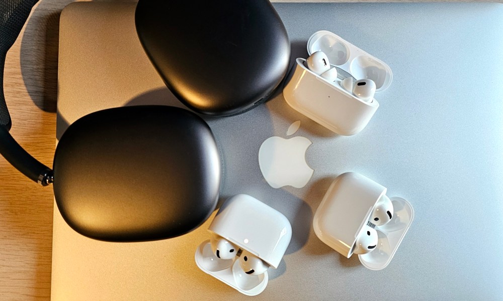 Apple AirPods and AirPods Max sitting on the lid of a MacBook Pro laptop.