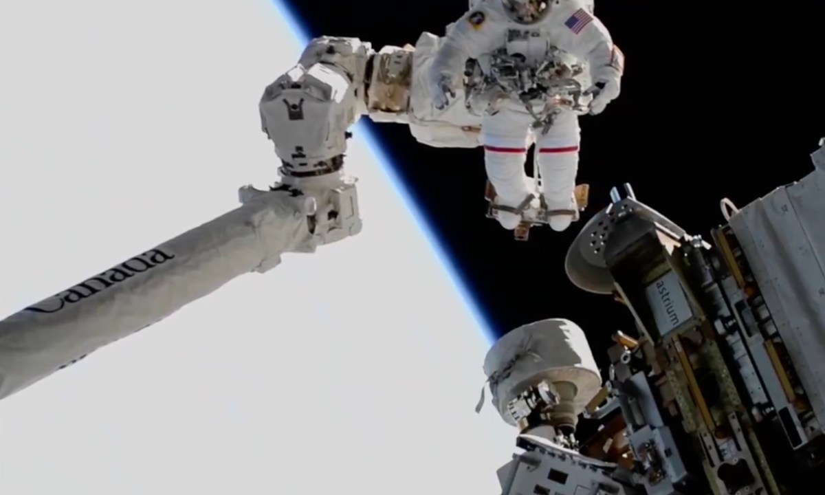 The Canadarm 2 robotic arm delivering Suni Williams to a worksite during a spacewalk outside the ISS.