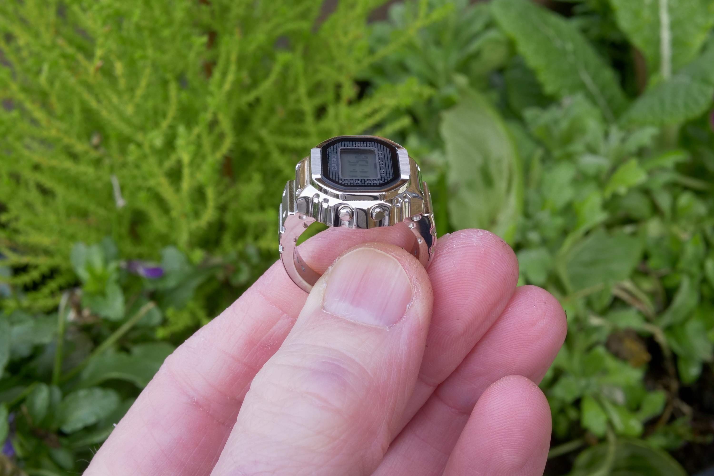 Человек, держащий часы Casio Ring, показывает кнопки.