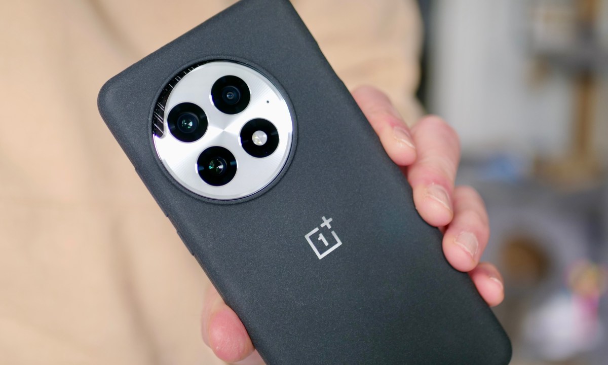 A person holding the OnePlus 13, showing the wireless charging insert in the camera cutout.