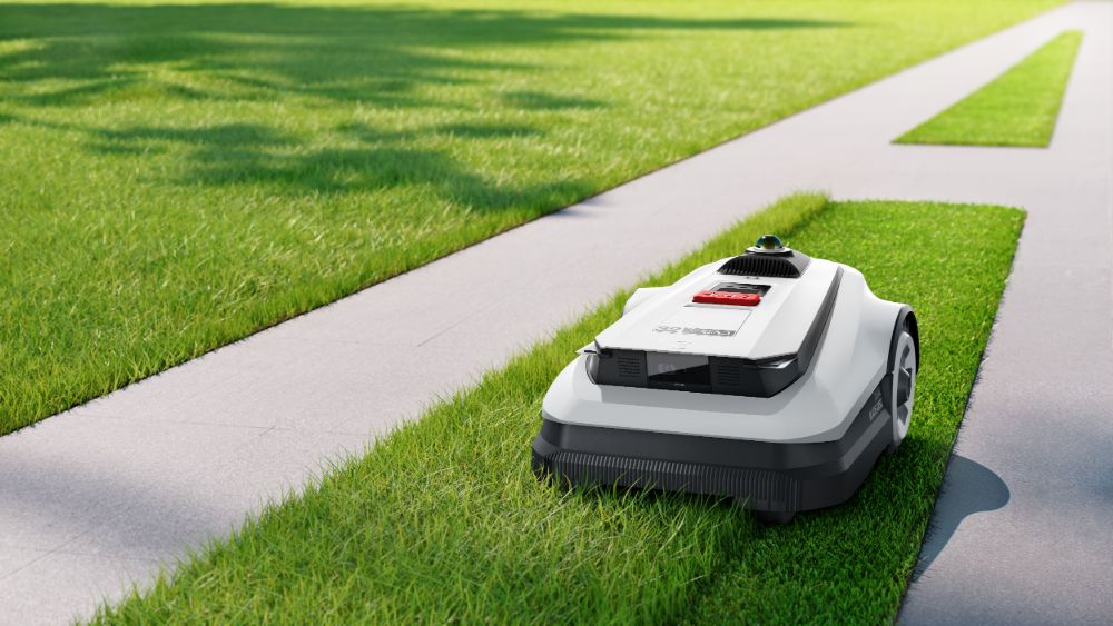 Ecovacs GOAT A1 3000 cutting grass near a sidewalk.