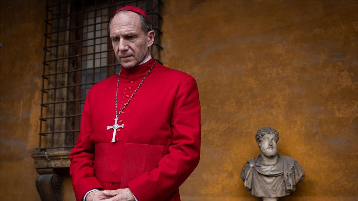 Ralph Fiennes looks very serious and red in a still from the movie Conclave.