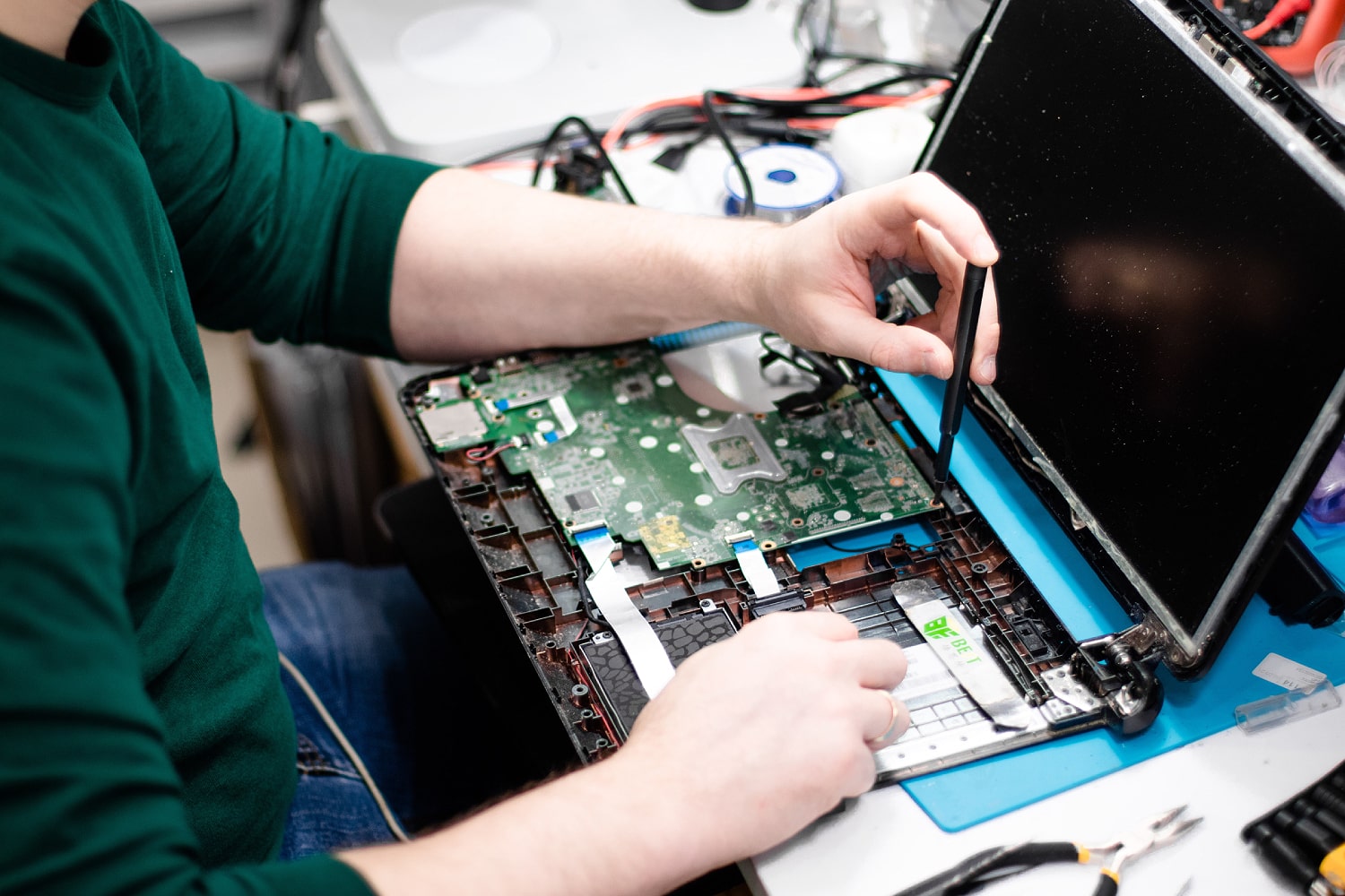 Someone repairing the inside of a MacBook with a small screwdriver.