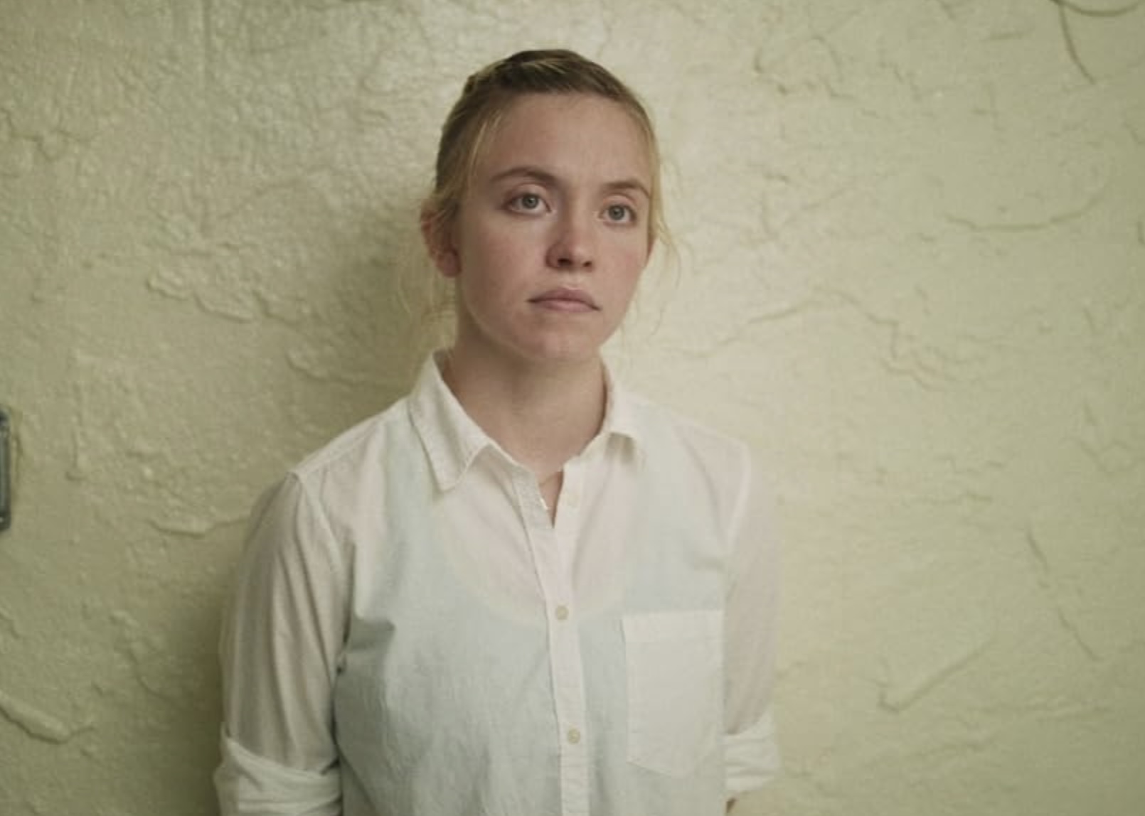 Sydney Sweeney stands in front of a wall.