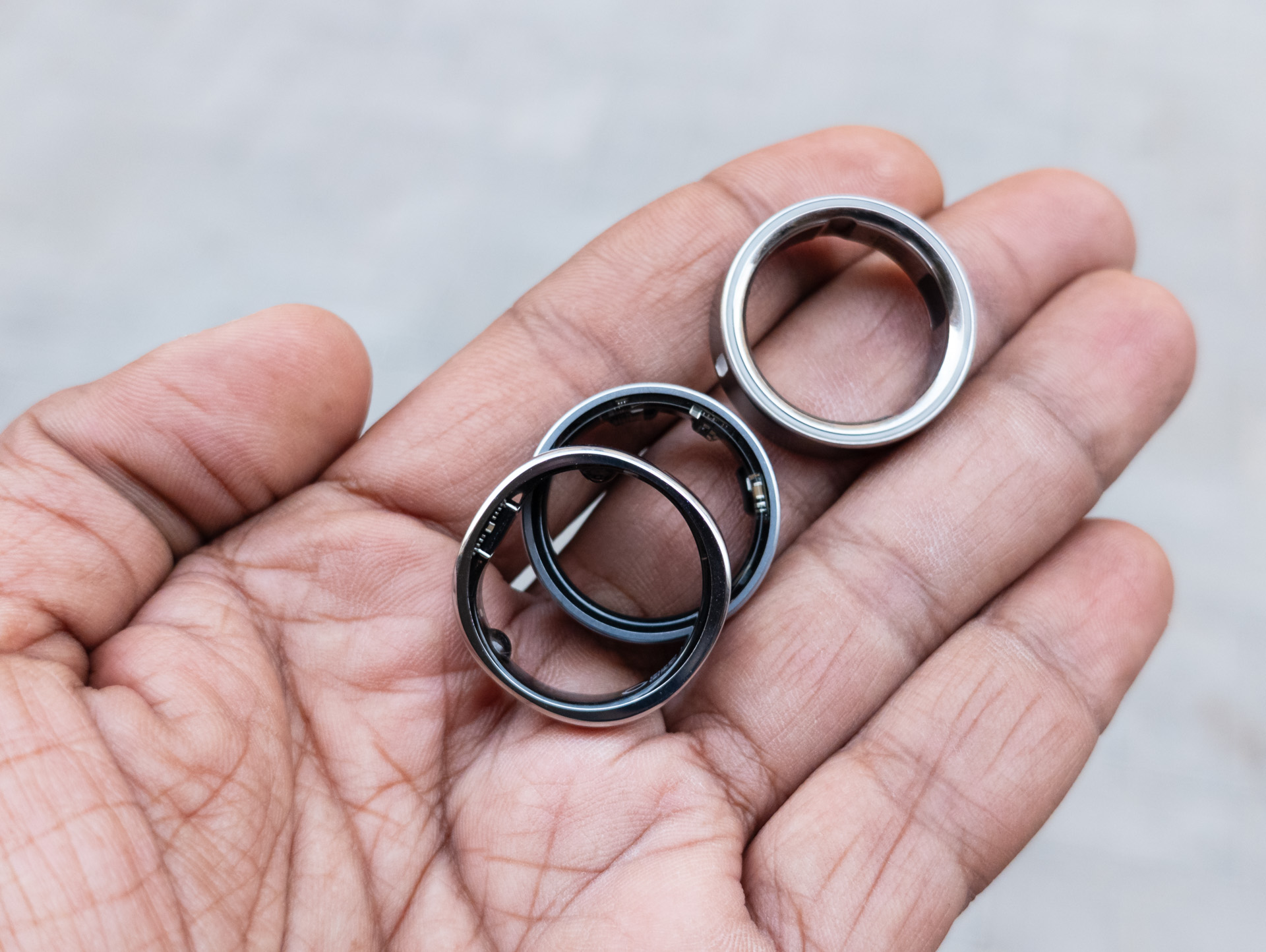 Oura Ring 4, Galaxy Ring und RingConn Gen 2 in einer Handfläche