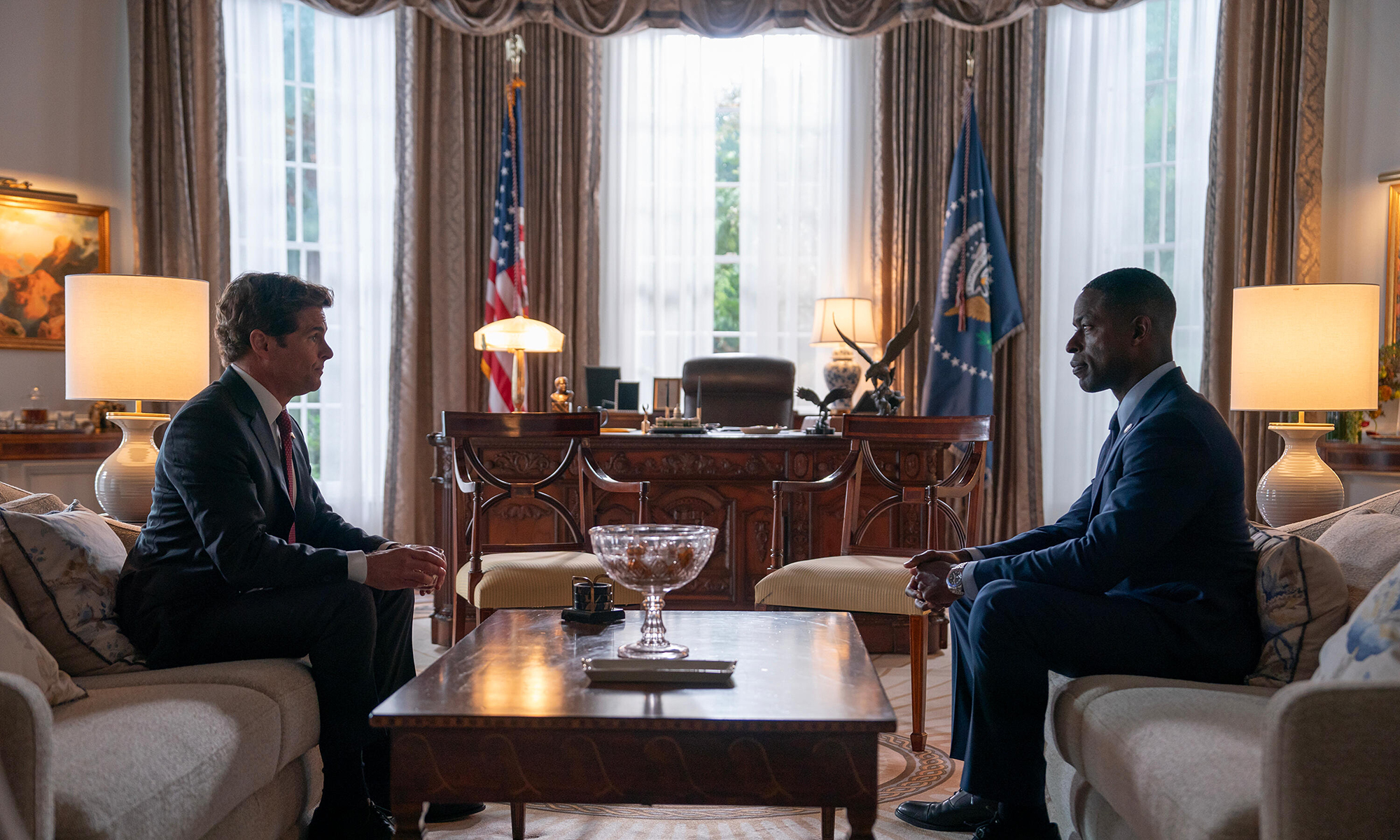 James Marsden e Sterling K. Brown sentados frente a frente em sofás no Salão Oval do Paraíso.