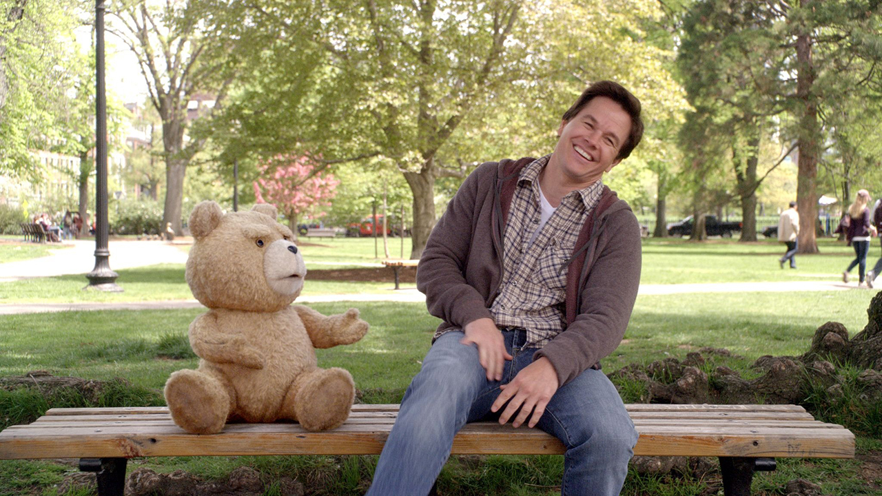 Ted y John Bennet se sentaron en el banco del parque se ríen en una película.