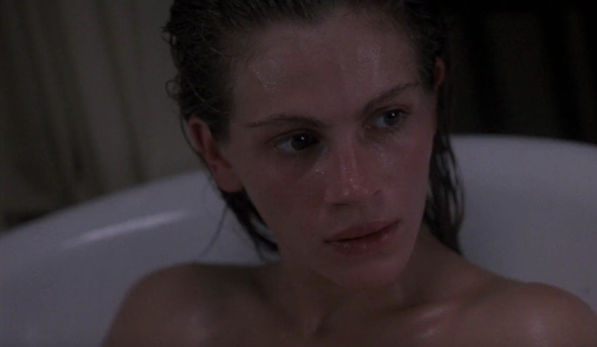 Julia Roberts sits in a bath tub and stares.