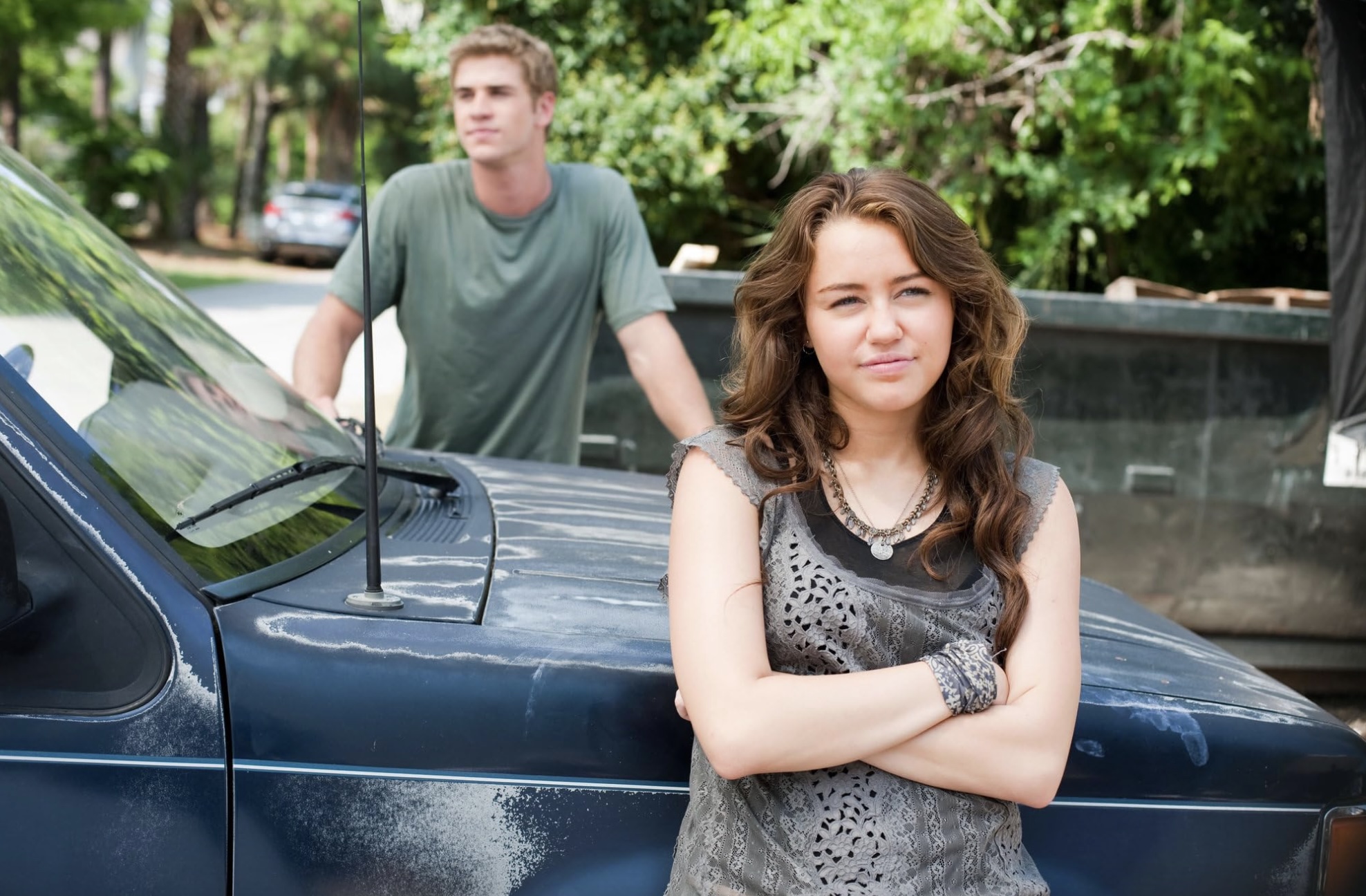 Miley Cyrus parada frente a un coche.